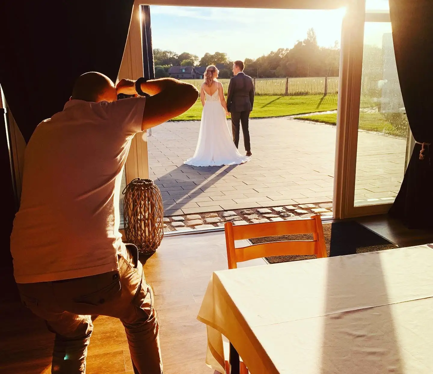 Ein Fotograf fotografiert ein Brautpaar im Gegenlicht auf der Terrasse