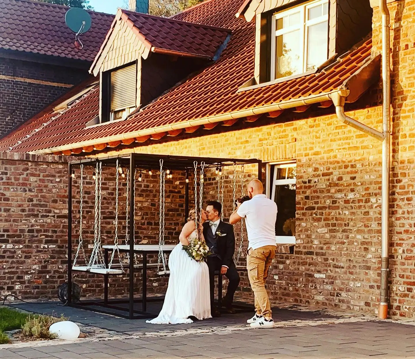 Brautpaar auf der Schaukel vor der Backsteinwand des Hofes