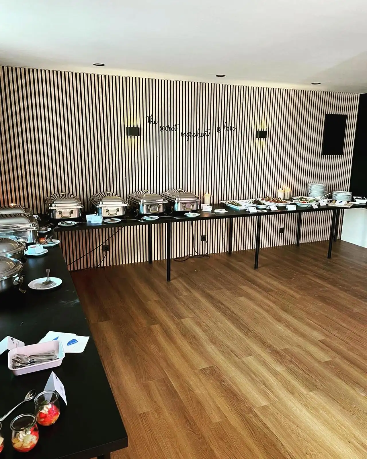 Buffet mit Warmhaltebehältern vor der Holzlamellenwand im Saal
