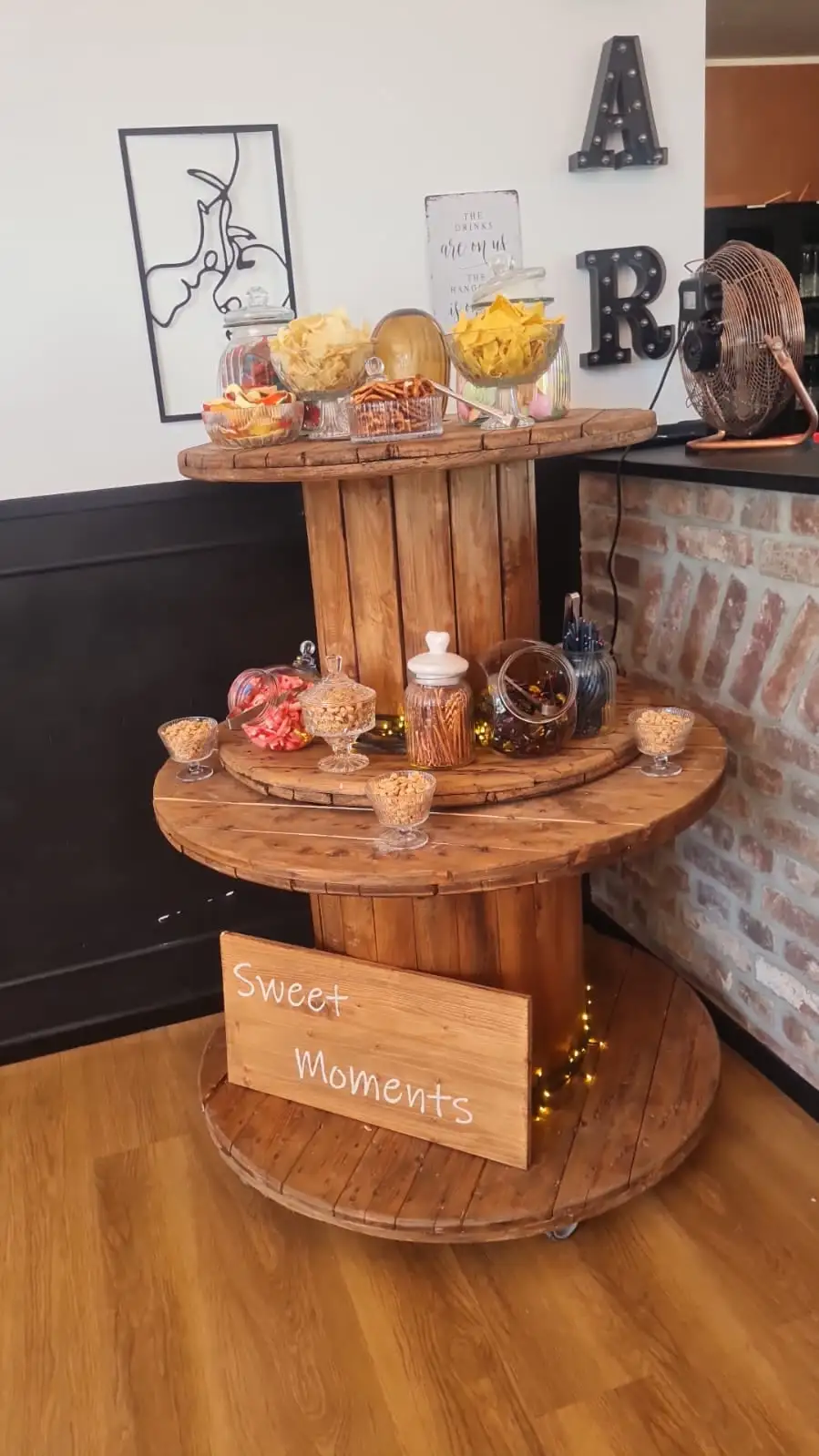 Candybar auf zwei Kabeltrommeln mit Gläsern voller Süßigkeiten und dem Schild „Sweet Moments“
