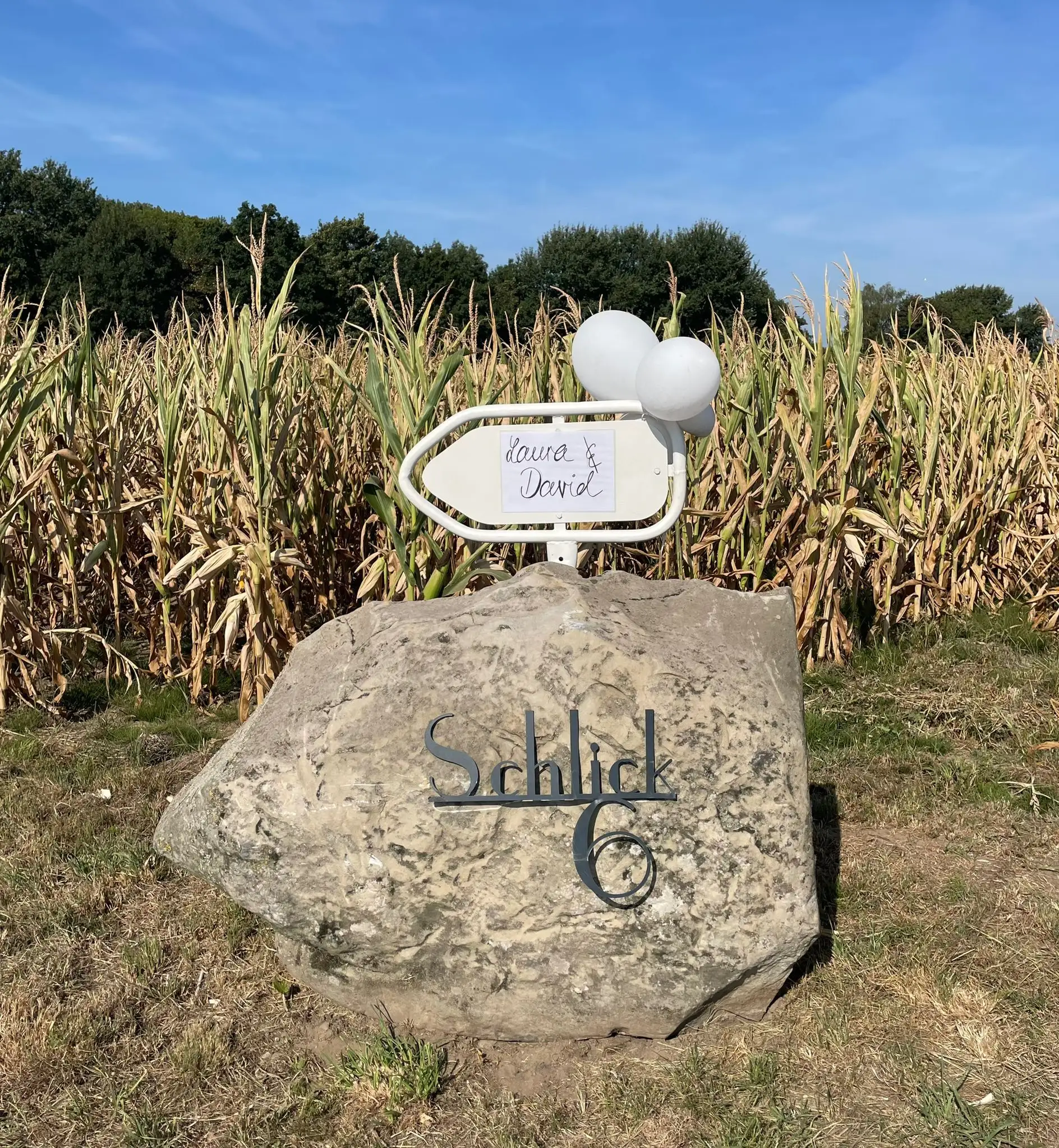 Findling mit der eingravierten Adresse „Schlick 6“ am Feldrand