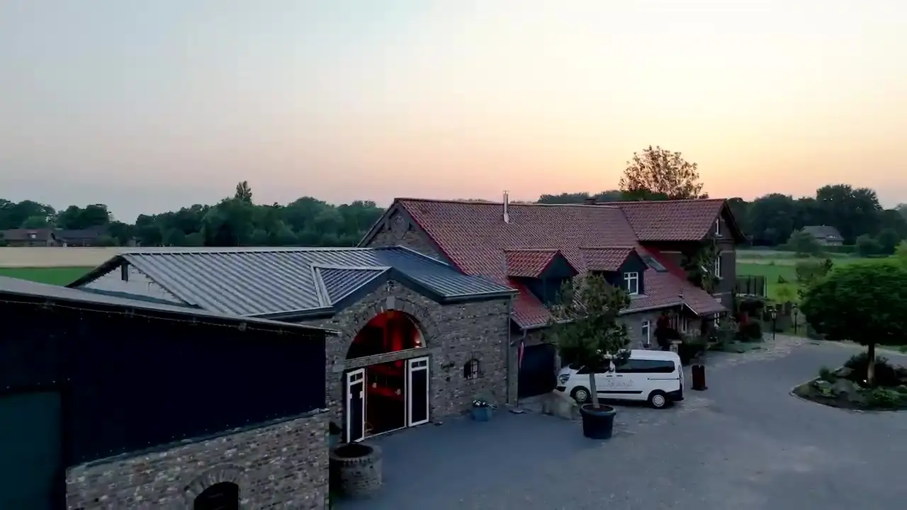 Luftaufnahme des Borghofs mit Scheune und Haupthaus bei Sonnenuntergang