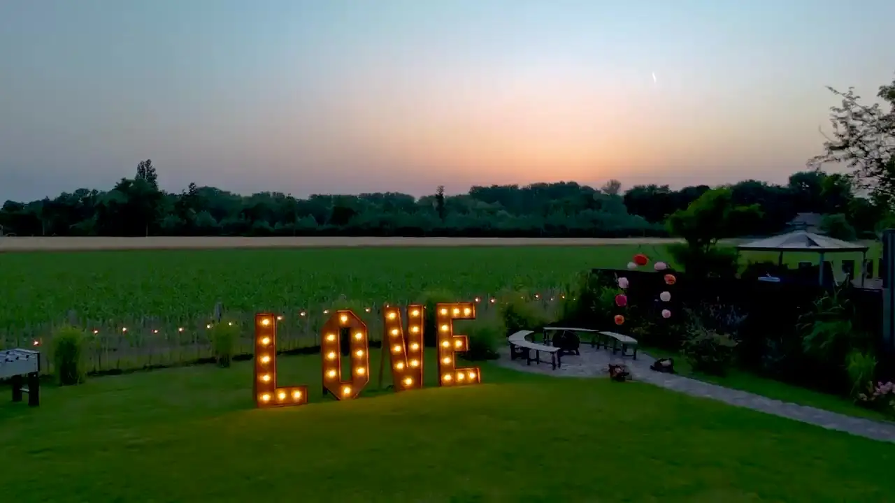 Beleuchteter LOVE-Schriftzug auf der Wiese in der Abenddämmerung