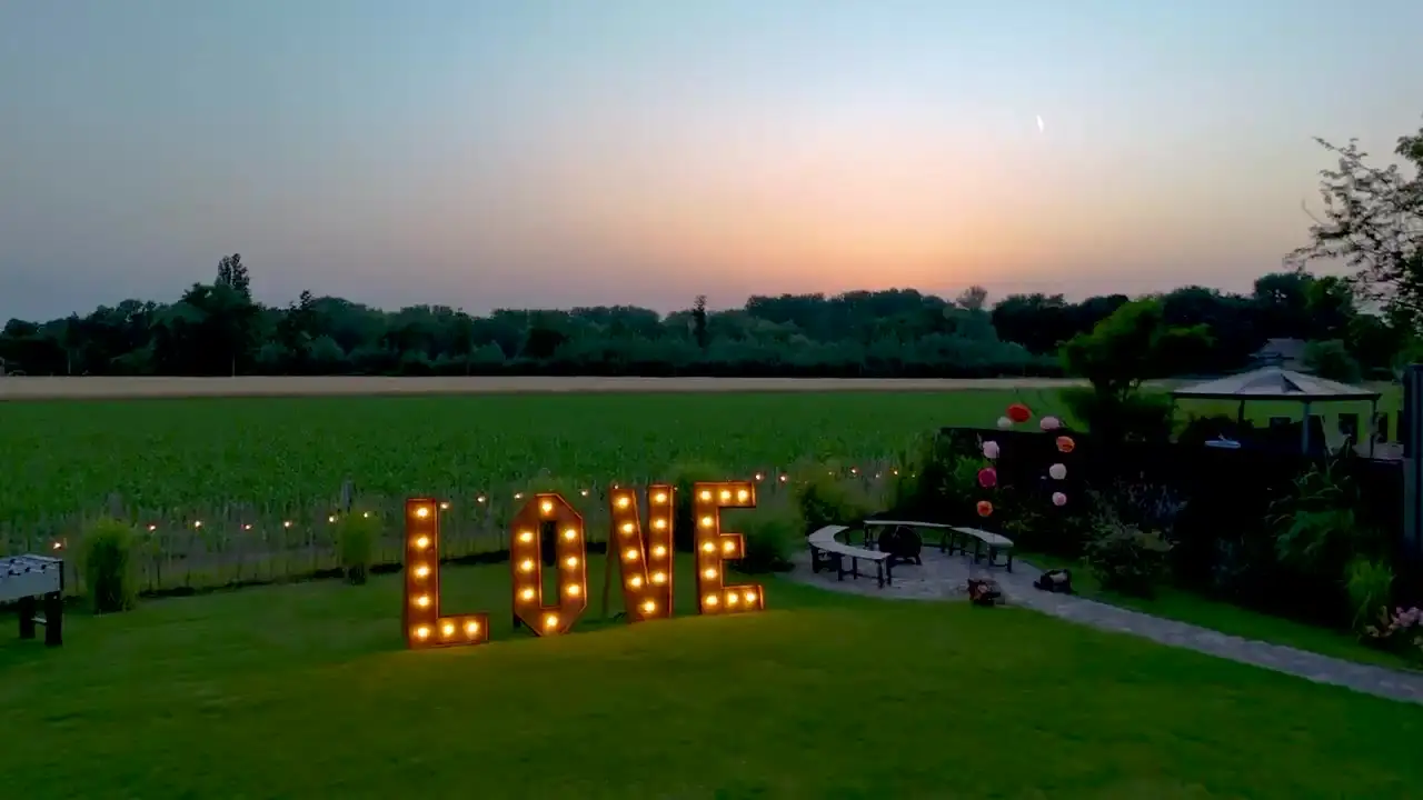 Beleuchteter LOVE-Schriftzug auf der Wiese in der Abenddämmerung