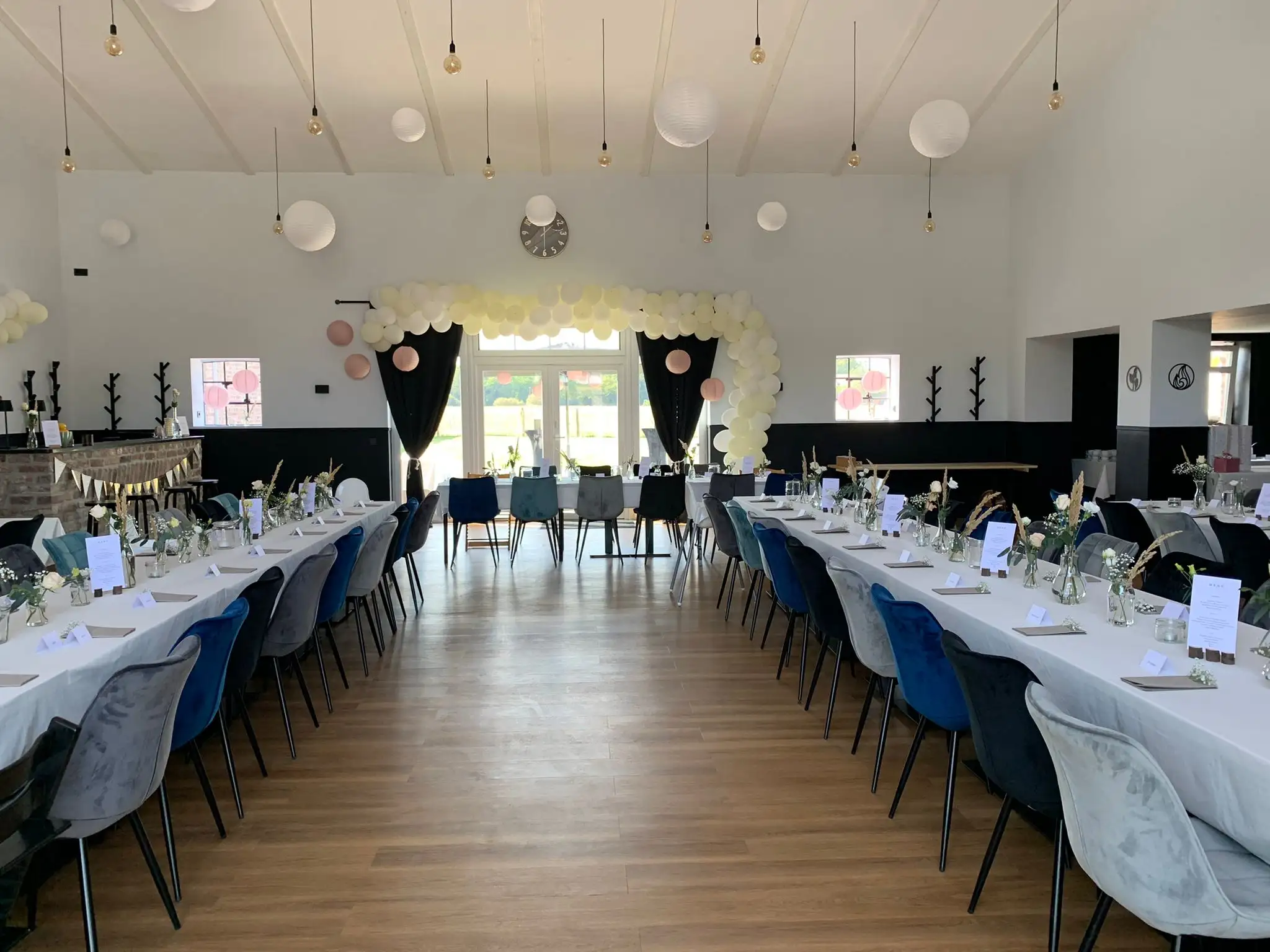 Saal mit langen Tafeln und weißen Lampions unter der Decke