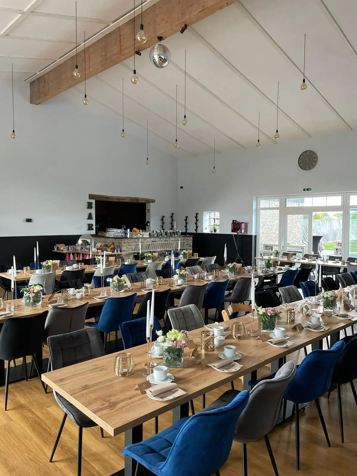 Lange Holztafel mit blauen und grauen Polsterstühlen im hellen Saal