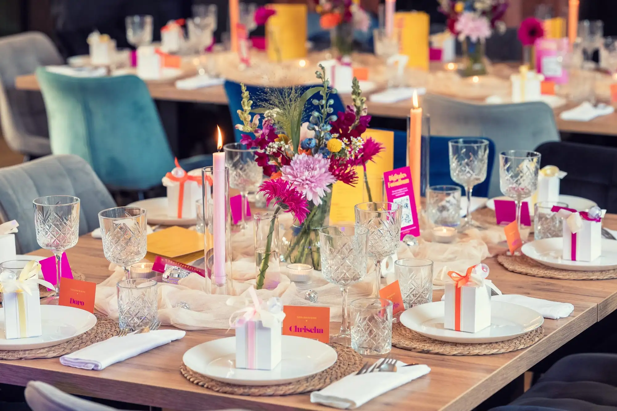 Bunte Tischdekoration mit Sommerblumen, Kerzen in Pink und Orange und Namenskärtchen
