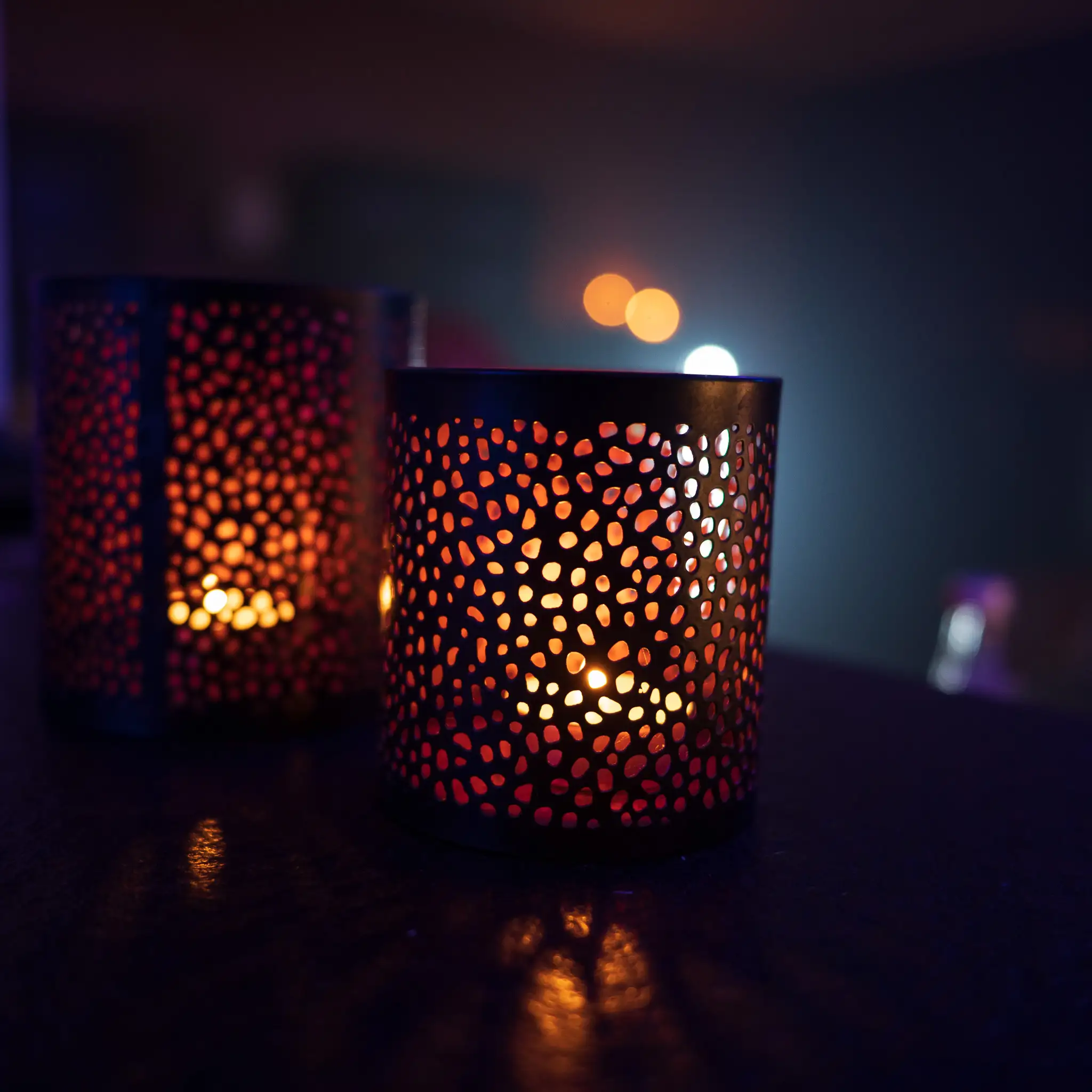 Zwei gemusterte Windlichter mit Kerzenschein auf dem Tisch